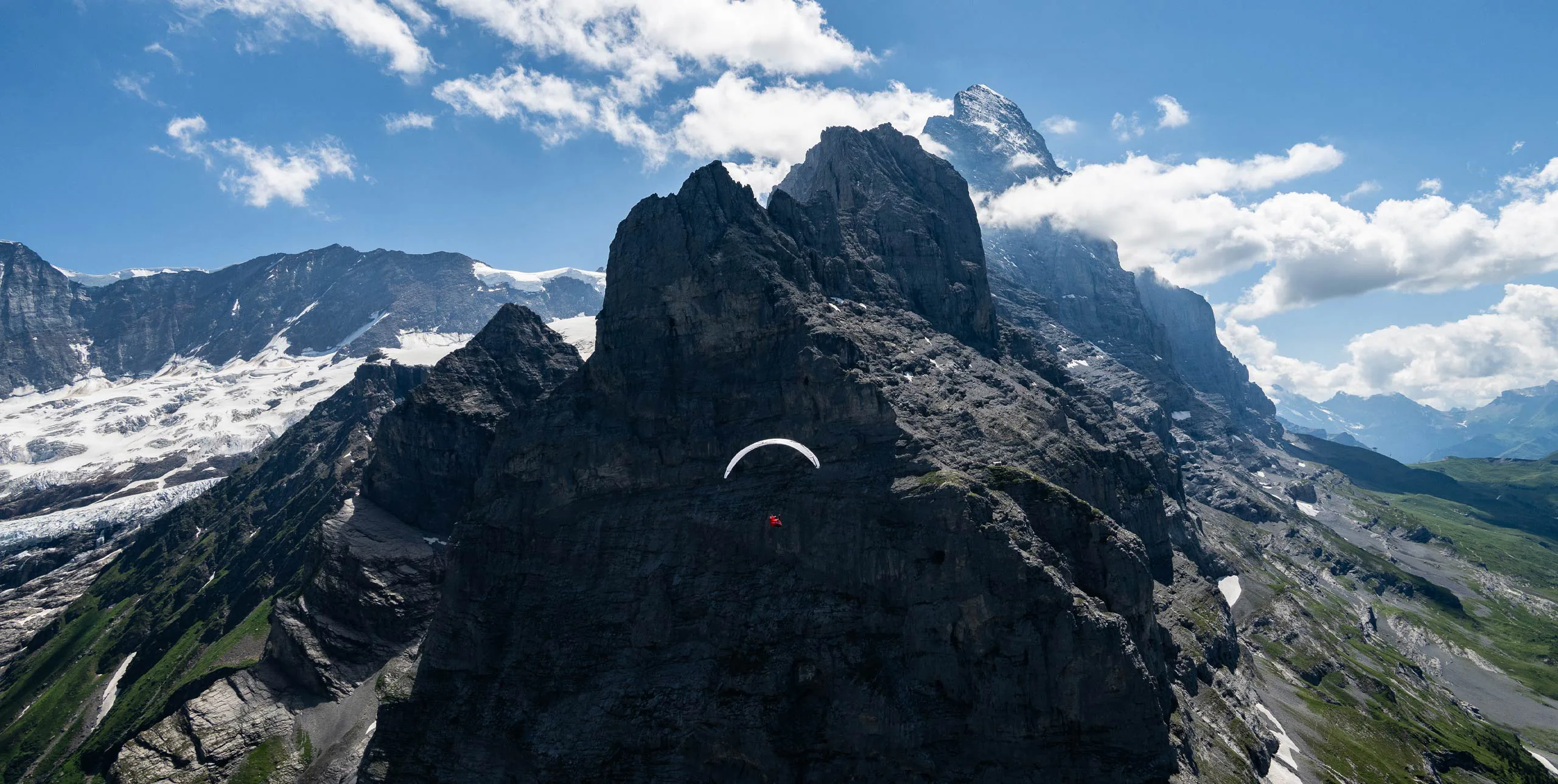一名滑翔伞选手在 Eigertour 2026 的瑞士高山岩壁前飞行